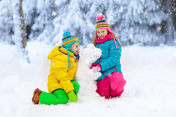 Kids making winter snowman. Children play in snow.