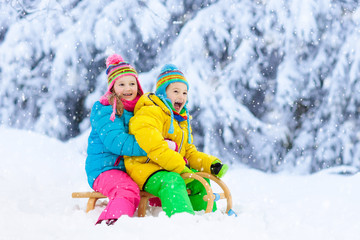 Fototapeta na wymiar Kids play in snow. Winter sled ride for children