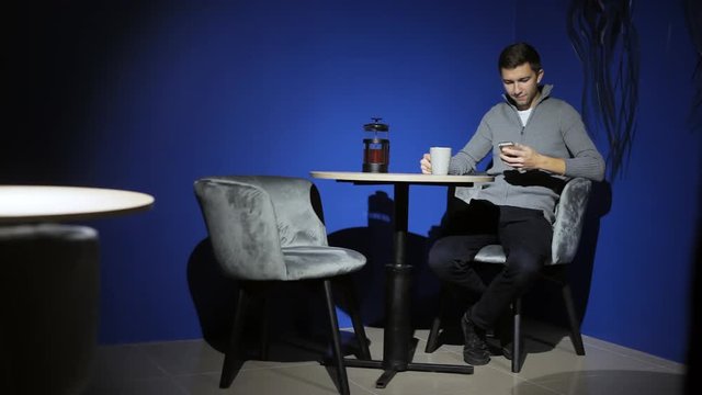 Man using smart phone and drink coffee in the bar, chek mails, browsing, reading, chatting with friends
