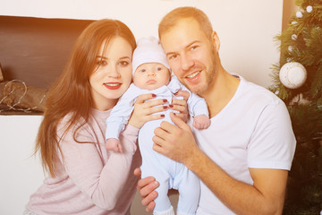 Handsome man and lovely woman embracing sweet baby and looking at camera