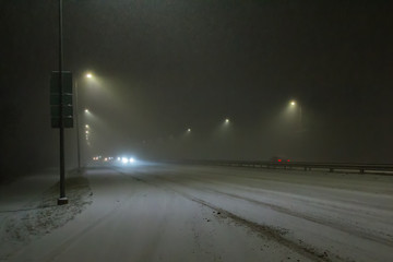 Cars on a highway in winter during heavy snowfall at night