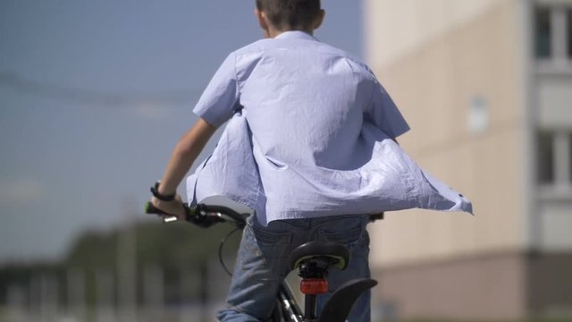 boy sits down on the bike and rides, slow motion