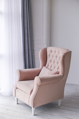 Pink armchair in living room near window.