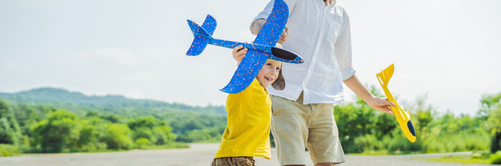 Happy father and son playing with toy airplane against old runway background. Traveling with kids concept BANNER, LONG FORMAT