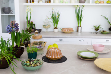 Modern kitchen with table, green flowers, cake.