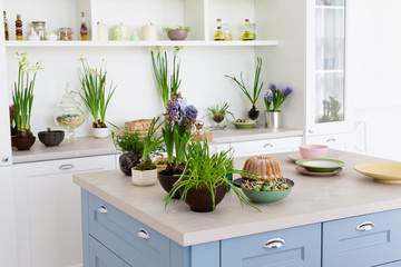 Modern kitchen with table, green flowers, cake.