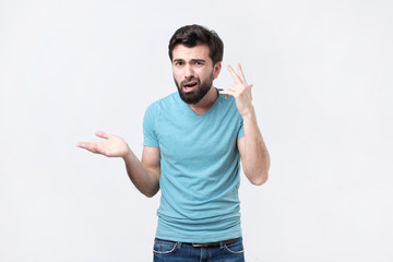 Angry mad young hispanic man gesturing with his finger against temple asking are you crazy....