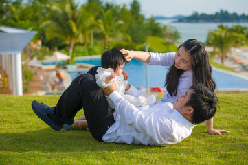 Naklejka na ściany i meble young cheerful and sweet wife and husband couple with mother and father playing with little daughter in Asian Korean family enjoying holidays tropical resort in love