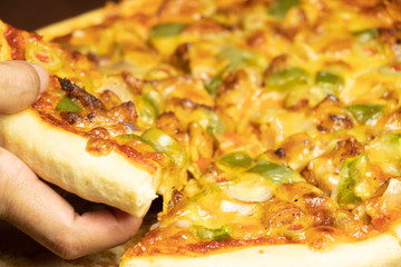 Pan Pizza slice take from hand side view with dark brown wood