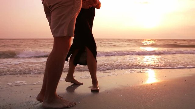 Sea side walk of young adult Couple in love with kiss moment on the sandy beach. Honeymoon concept video.