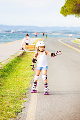 A little caucasian girl beginner roller on the seaboard. Rollerblading and outdoor activity concept