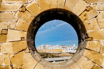 View of the walled medina of Essaouira through a circular brick window at the Skala du Port bastion in Essaouira on Morocco's Atlantic coast