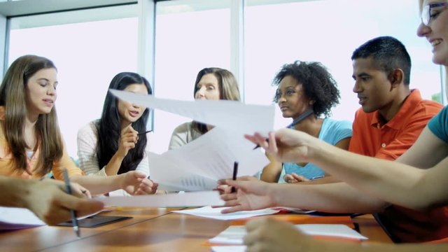 Teen multi ethnic boys and girls university class in tutorial with Caucasian American female college lecturer  