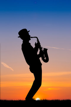 man plays the sax at sunset