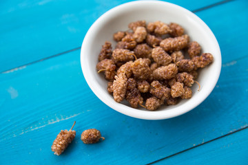 dried mulberries on wooden turquoise background