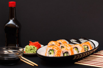 Uramaki California. Sushi rolls, bottle and bowl with soy sauce.