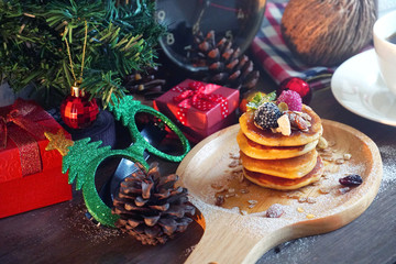 Pancake topping with berries and nut with background gift and pine cone under christmas tree, holiday party dessert