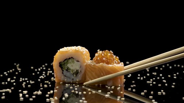 sushi roll with salmon and caviar on black background rotating.