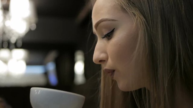 Young girl drinking a cup of tea in the restaurant