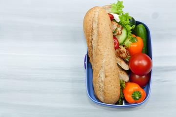 Lunch box with sandwich and vegetables.