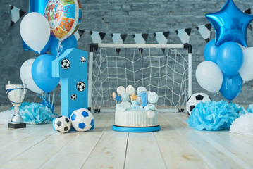 Festive background decoration for birthday with cake, letters saying one and blue balloons in...