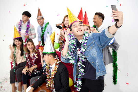young asian man selfie or take a photo of Group happy  people having fun on the red sofa celebrating together in party on white background. friends . new year . funny