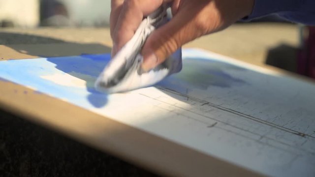 Painting process of the aquarel picture on painters table on the street