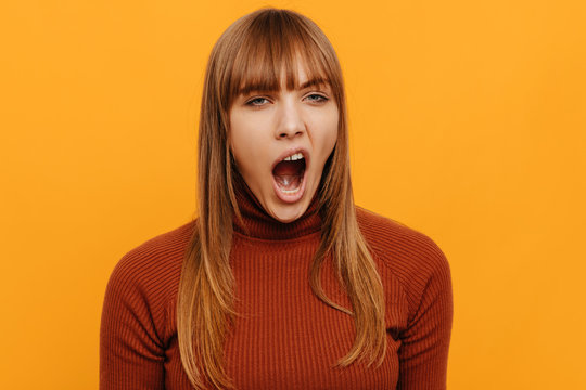 Woman portrait. Emotion. Girl is yawning, on a yellow background