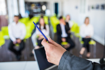 Close up of male mentor or coach hold paperwork, give flipchart presentation, talking with employees. Businessman have conversation with workers at briefing, discussing business plan or project