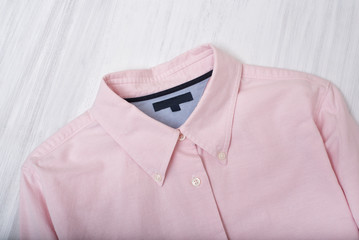 Collar of pink shirt on wooden background. Fashionable concept