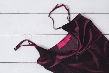 Burgundy velvet dress BOOHOO on a white wooden background. Close up. Fashion concept