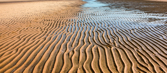 The wet sand waves on the beach