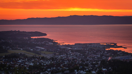 Sunset sky and distant city Ranheim in Norway. Distant sea view.