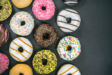 assorted donuts with different fillings and icing on a black background. top view 