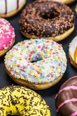 assorted donuts with different fillings and icing on a black background. top view 