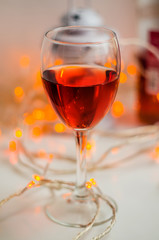 A glass of wine with garland with warm cokeh lights at the blurred background
