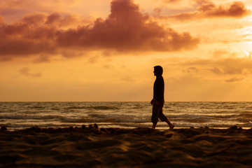 Man walks and thinks at sunset on the beach