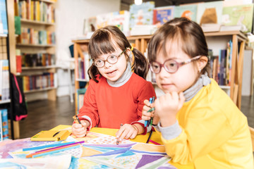 Fototapeta premium Two sisters with light Down syndrome wearing red and yellow sweaters
