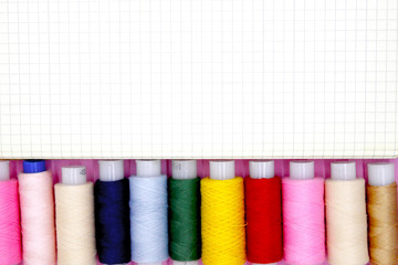 Bright sewing thread on a pink backing. View from above. Free space for your text.