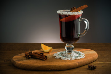 Traditional Christmas hot drink - mulled red wine - with spices, cookies and fruits on a wooden rustic table.