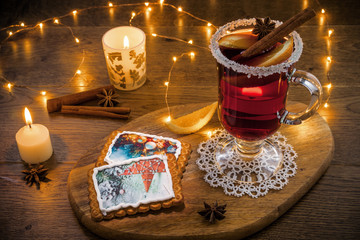 Traditional Christmas hot drink - mulled red wine - with spices, cookies and fruits on a wooden rustic table.