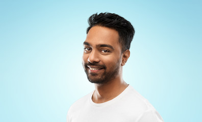 Fototapeta premium people concept - smiling young indian man over blue background