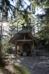 Fototapeta na wymiar Small chapel in the forest in germany bavarian forest - Osserkapelle on the Osser. With heavy lensflare.