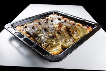 Turbot fish in baking pan oven with potatoes olives and aromatic herbs