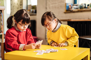 Two sunny children feeling involved in looking at learning cards