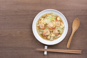 top view of stir fried cabbage with shrimp in a ceramic dish on wooden table. asian hommade style food concept.