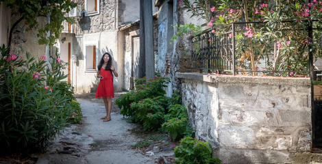Fototapeta na wymiar Young girl standing in alley in Greece village