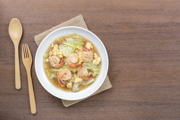 top view of stir fried cabbage with shrimp in a ceramic dish on wooden table. asian hommade style food concept.