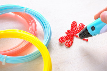 Human hand holds a red plastic dragonfly from an ABS/PLN plastic
