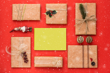 Christmas composition. Frame made of Christmas gifts, pine branches, toys on red background with snow. Flat lay, top view.